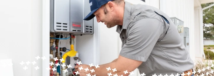 HVAC technician servicing an outdoor tankless water heater during residential plumbing maintenance.
