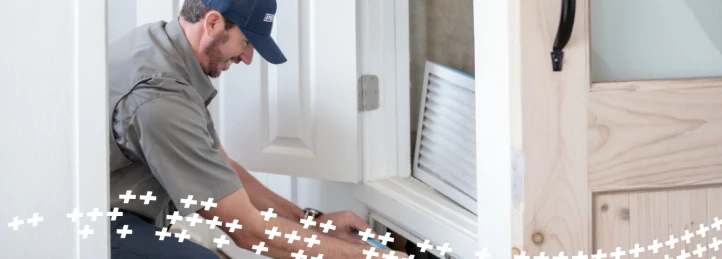 HVAC technician replacing an indoor air filter during residential heating and cooling maintenance service.