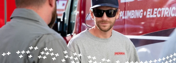 Peaden service technicians talking beside a branded HVAC, plumbing, and electrical service van.
