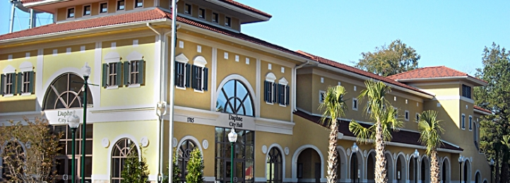 Daytime City Hall building with palm trees, arched windows, and Mediterranean-style architecture.
