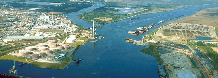 Aerial view of industrial port, river, and bridge in Chickasaw, Alabama with storage tanks and barges.