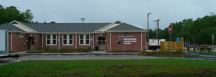 Leon County Chocktawhatchee Community Center brick building with parking lot and stop sign on a cloudy day.