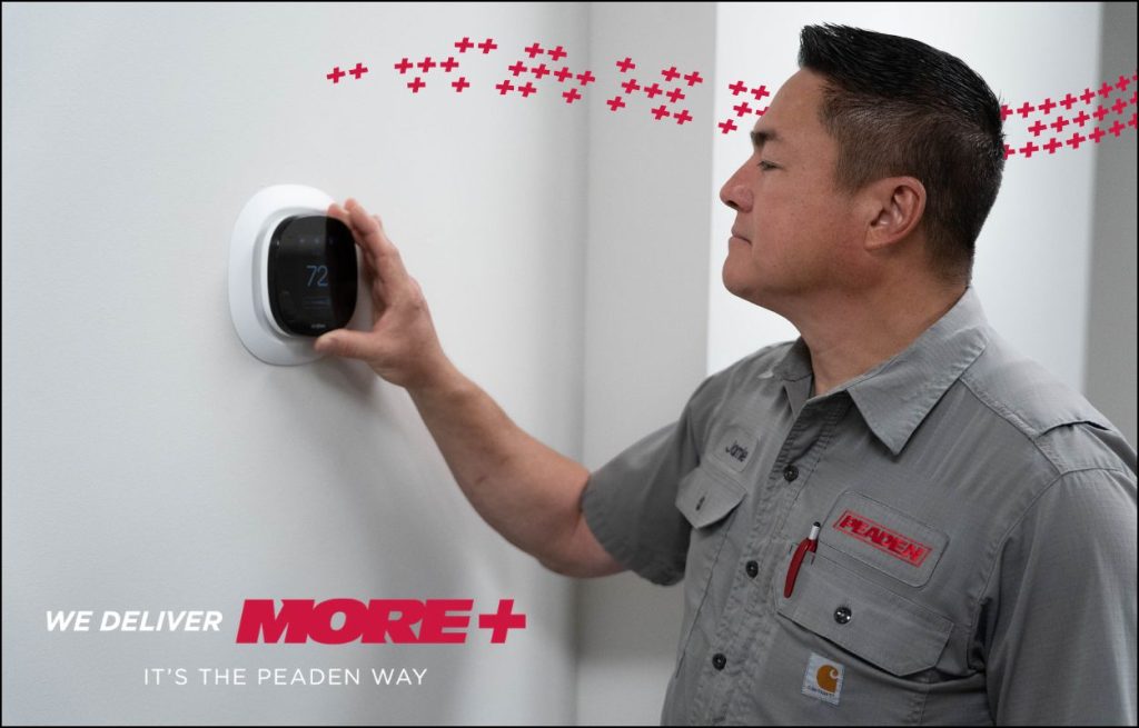 A Peaden HVAC tech adjusting a smart thermometer