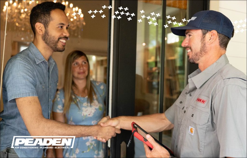 A couple greeting the hvac tech and shaking hands at the door.