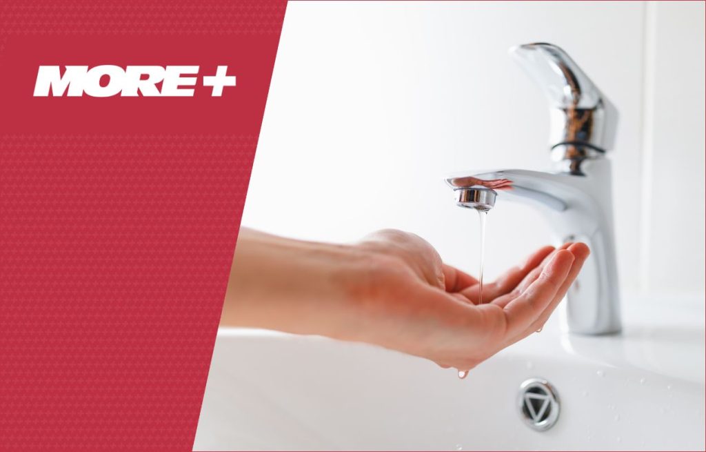 A hand under a faucet with low flow water from back flow.