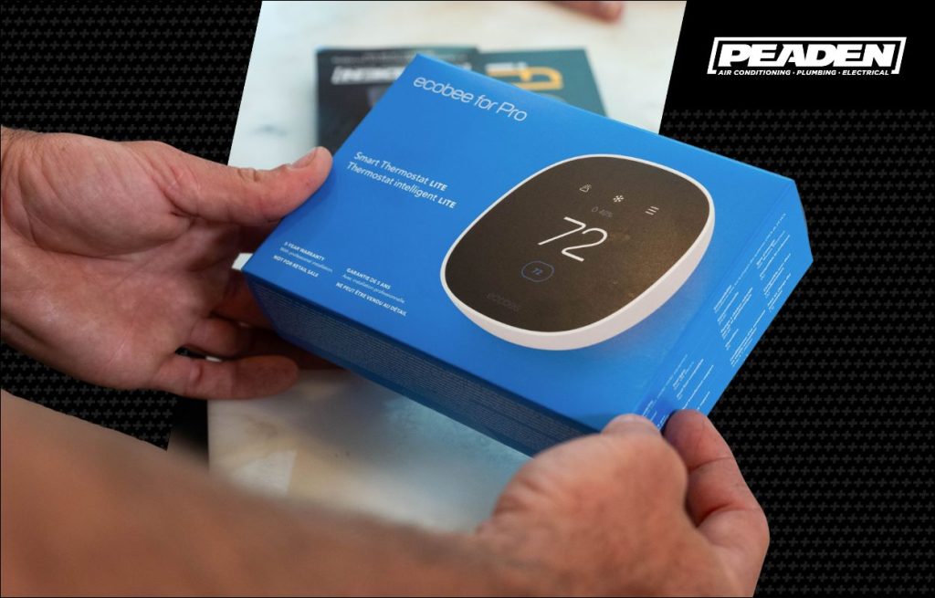 A Peaden HVAC tech holding a smart thermostat.