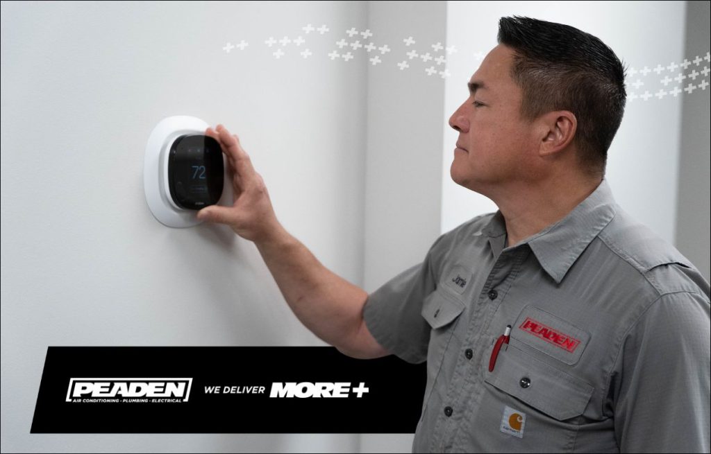 A Peaden HVAC tech adjusting a smart thermostat.