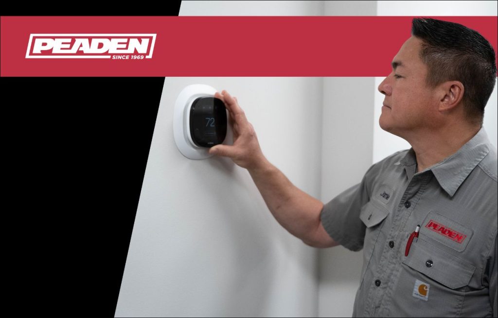 A Peaden HVAC tech adjusting a smart thermostat.