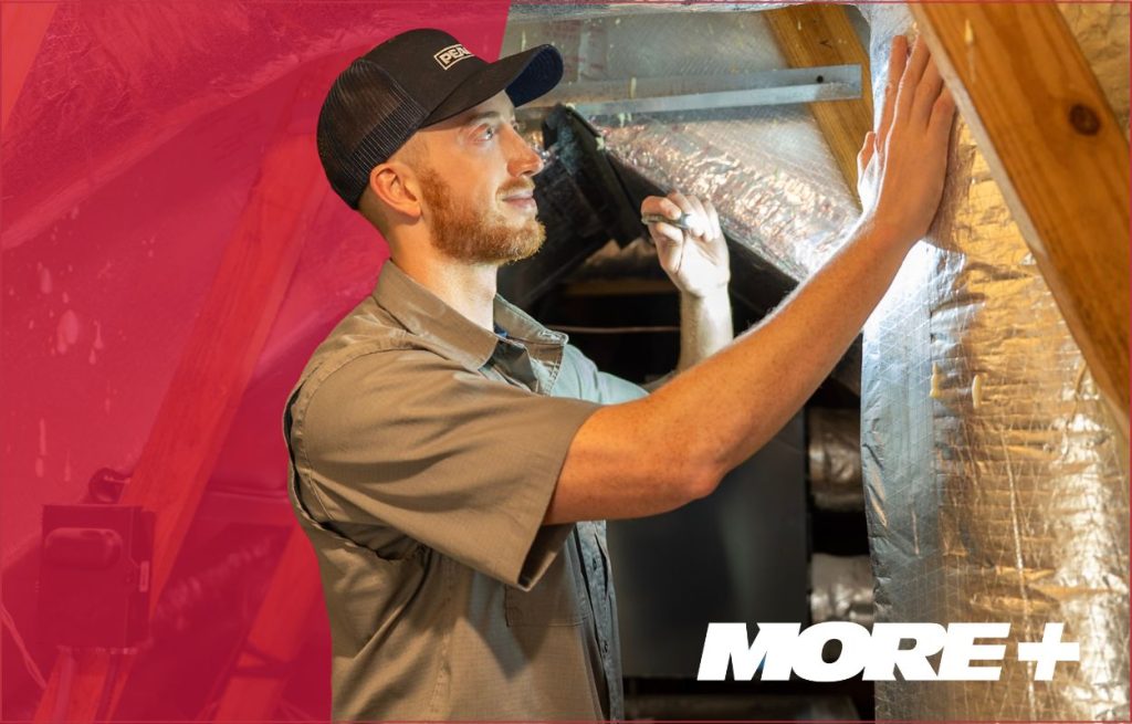 An HVAC technician checking the ductwork in the attic