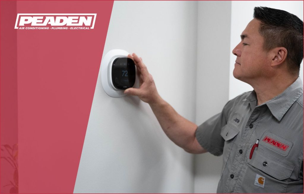 A Peaden HVAC tech adjusting a smart thermostat.