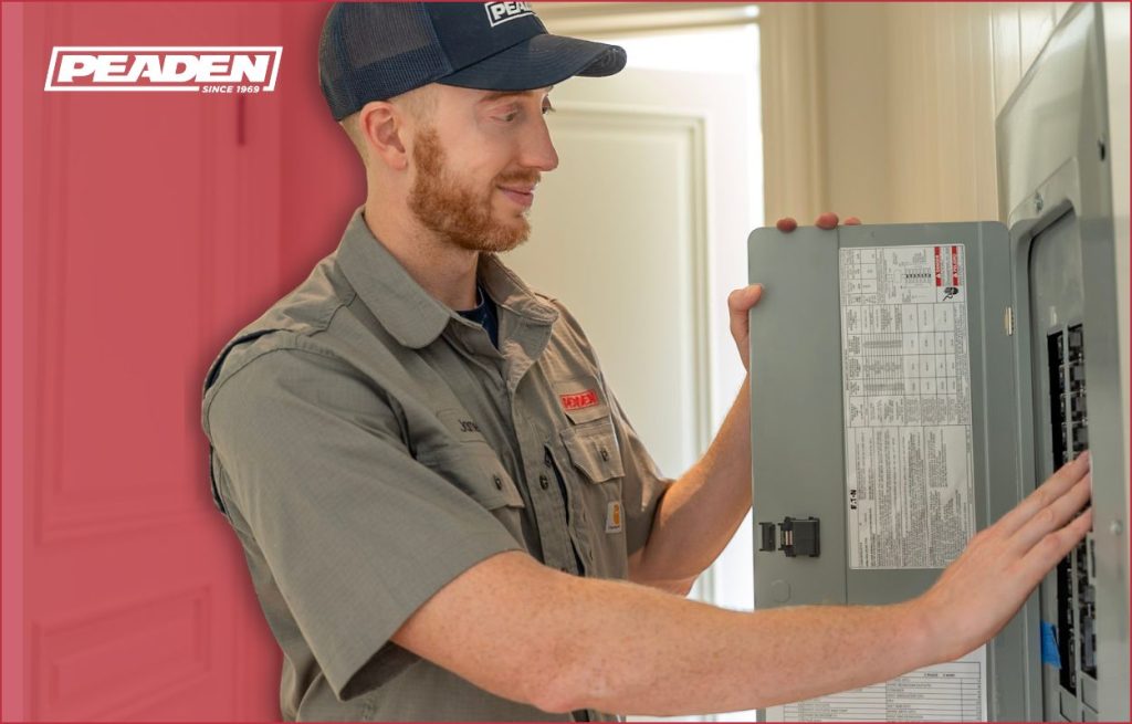 A Peaden Electrician working on a breaker box looking on.