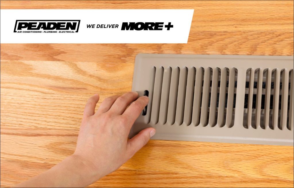 A woman feeling the air from her AC vents and finding it warm.