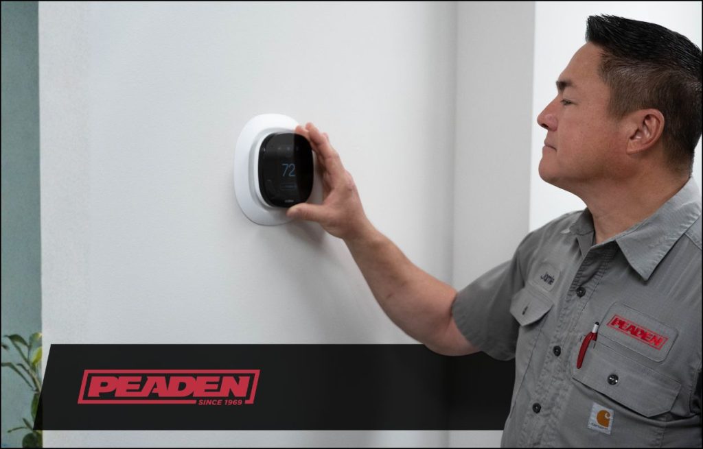 A Peaden HVAC tech checking a thermostat