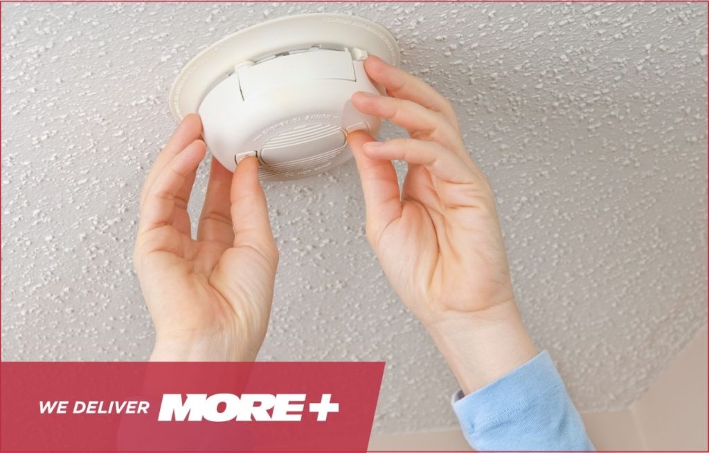 A homeowner checking his smoke detector.