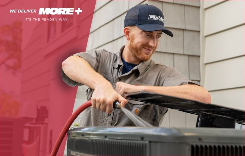 A Peaden HVAC tech cleaning an AC unit.