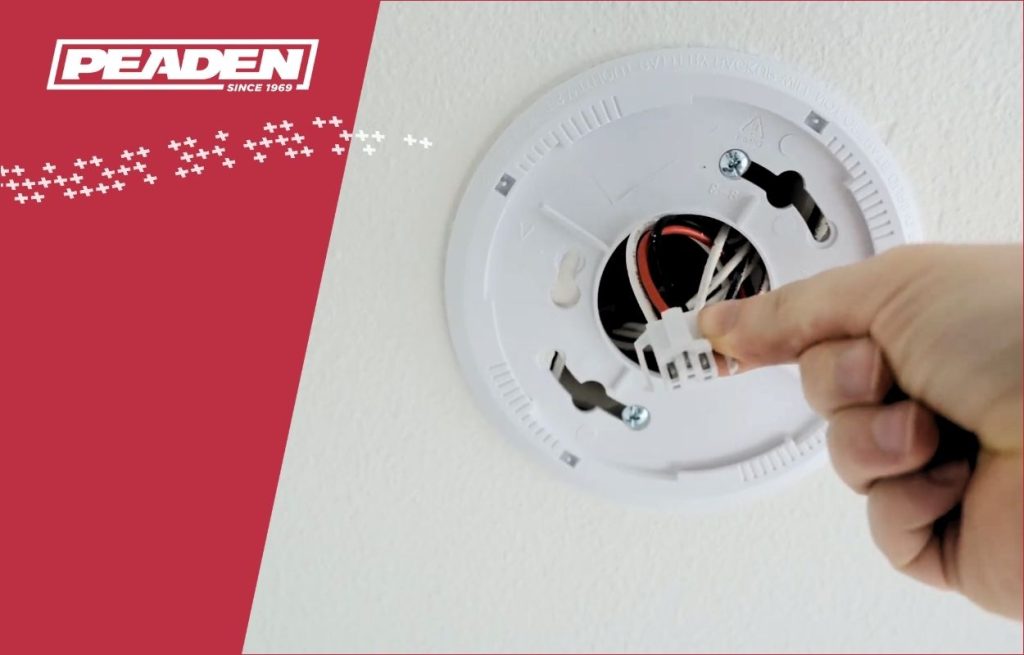 A Peaden Electrician checking a smoke detector.