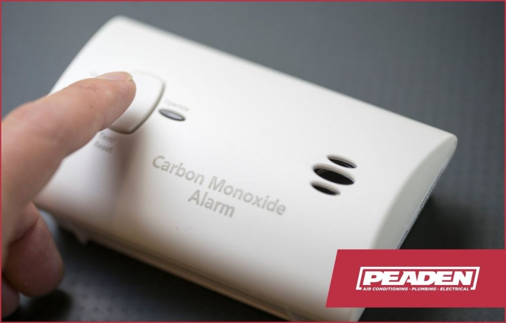 A homeowner testing a carbon monoxide detector.