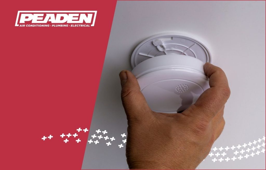 A Peaden Electrician checking a smoke detector.